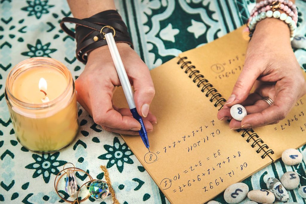 Personne notant le nombre 222 dans un carnet, avec une tasse de thé sur une table.